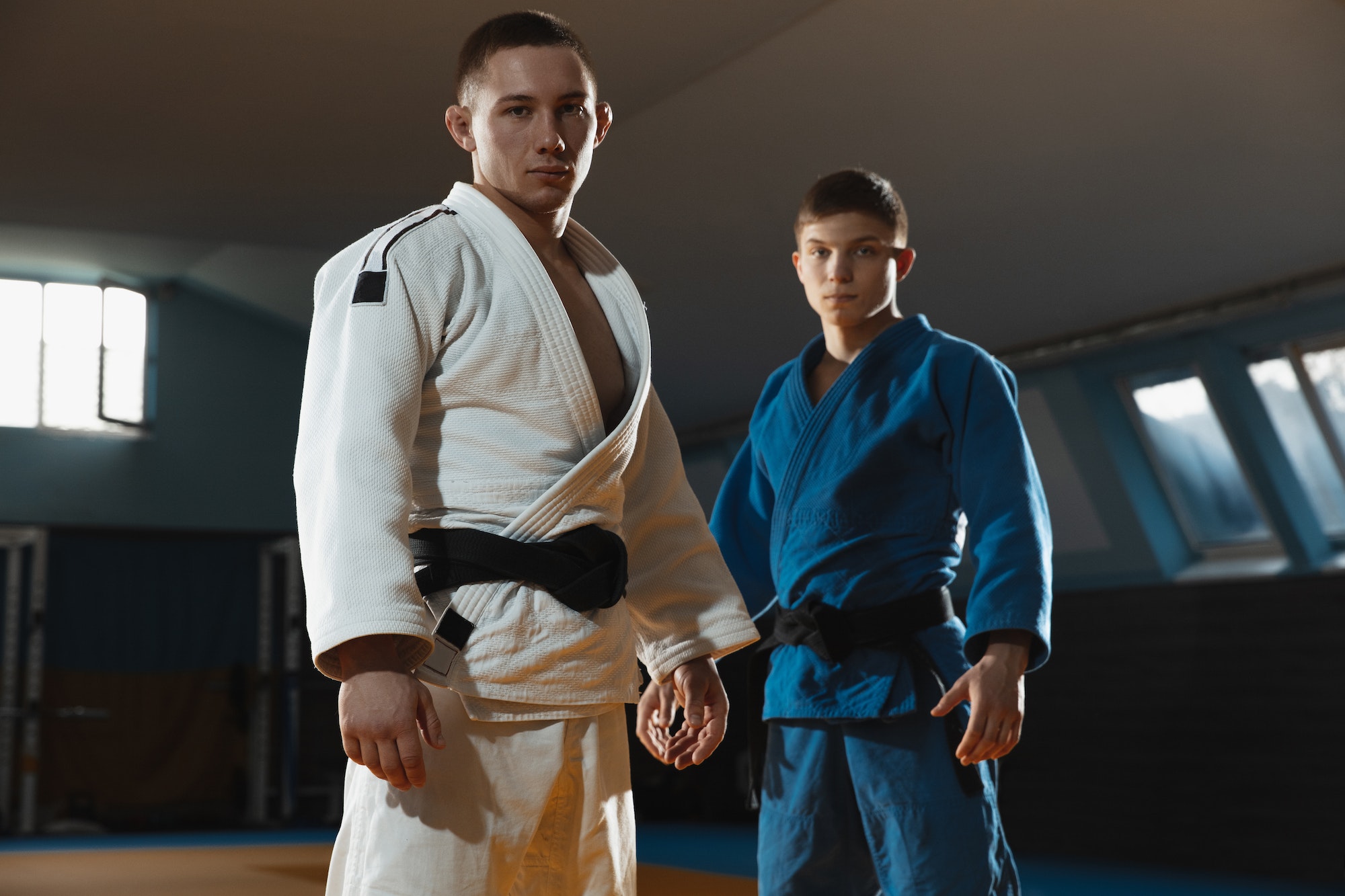 Two young judo fighters in kimono posing comfident in the gym, strong and healthy